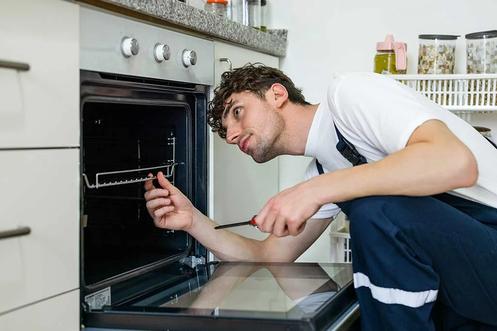 Repair specialist inspecting the inside of a built-in kitchen oven